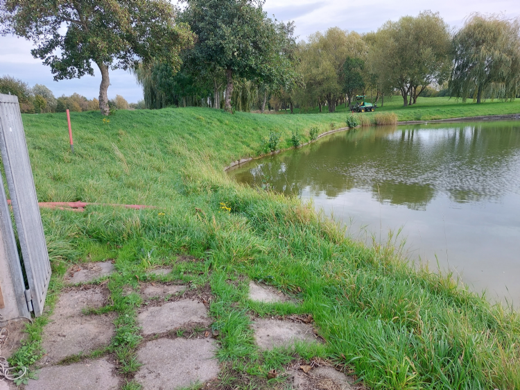 Het waterbassin aan de rand van de golfbaan. Links het pompgebouwtje