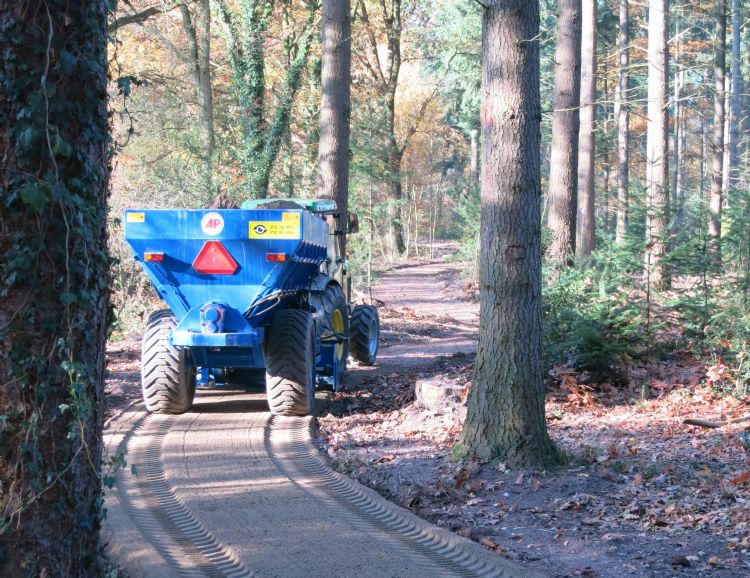 Met een speciaal gefabriceerde kar met afwerkbalk achter de trekker wordt de Graustabiel® vanuit het depot naar de plaats van verwerking gereden en over de geprofileerde onderbaan verspreid. Het omliggende terrein wordt daardoor niet bereden.