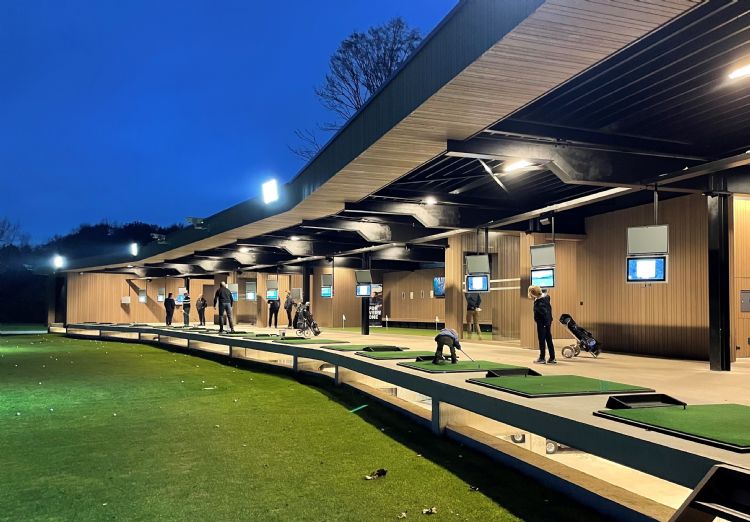 De fraai verlichte drivingrange met schermen van Toptracer op golfbaan Palingbeek op een winteravond