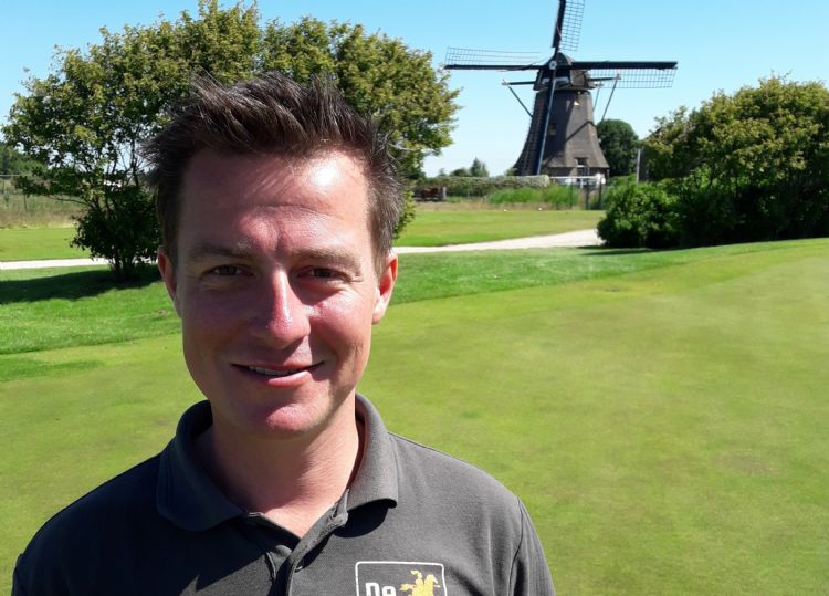 René van der Mespel met op de achtergrond de watermolen die als gemaal voor de golfbaan dient.